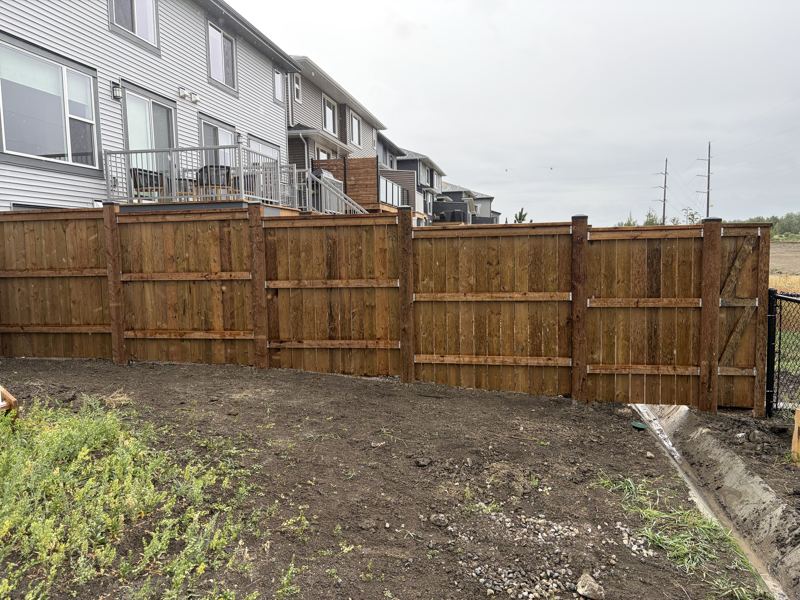 Long run of new wood fence stepping down a sloped property line
