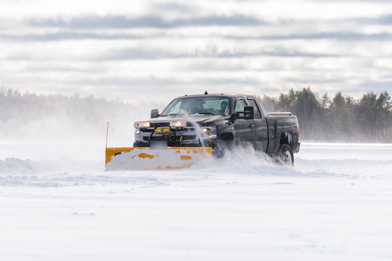 Pickup truck with a plow clearing deep snow on an open lot